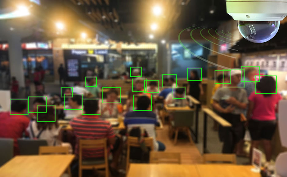 顔認識技術を示す画像。監視カメラが店内の人物の顔を認識し、緑色の四角で囲んでいます。