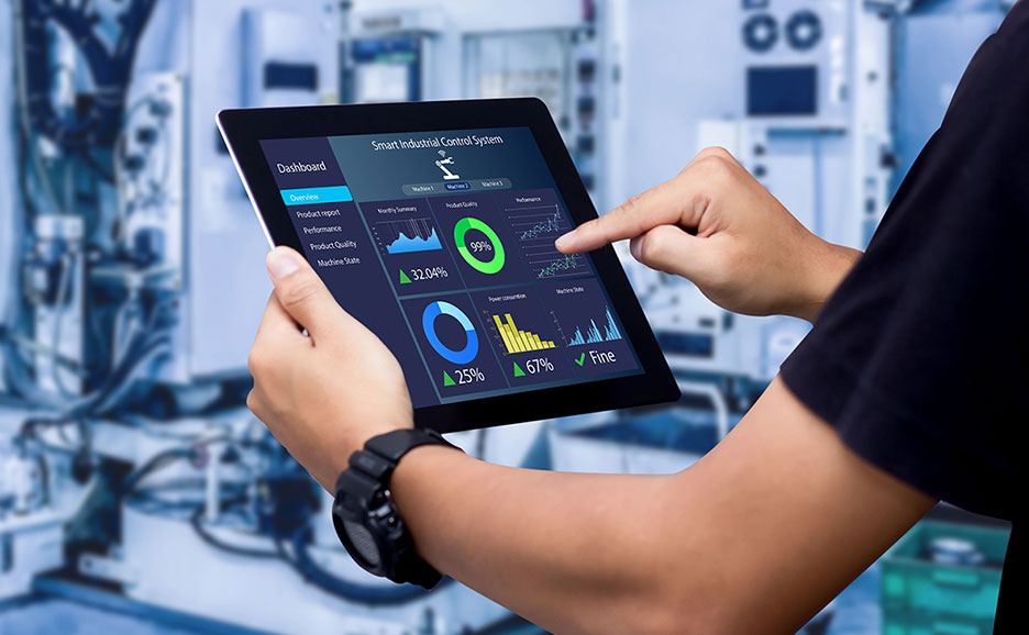 作業員が工場でタブレットを操作し、スマート産業制御システムのダッシュボードをチェックしています。