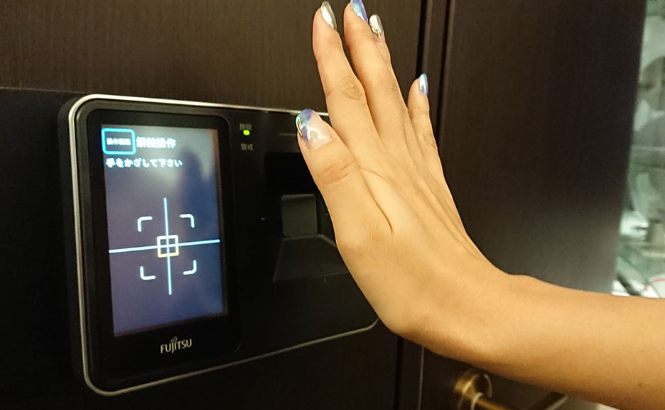 ネイルをした手が、富士通製の手のひら静脈認証装置にかざされており、認証を試みている様子