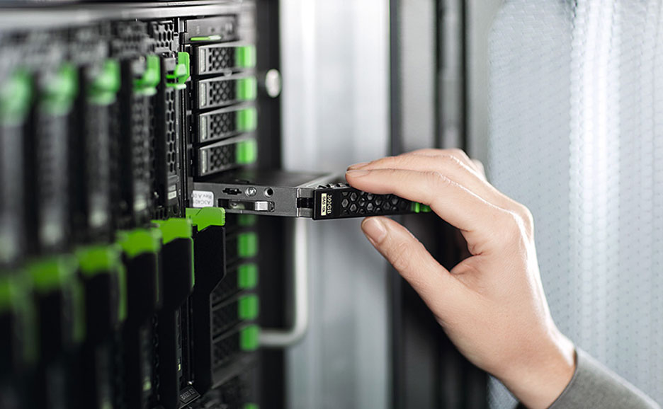 データセンターで、技術者がサーバーラックからストレージドライブを取り外しているクローズアップ画像