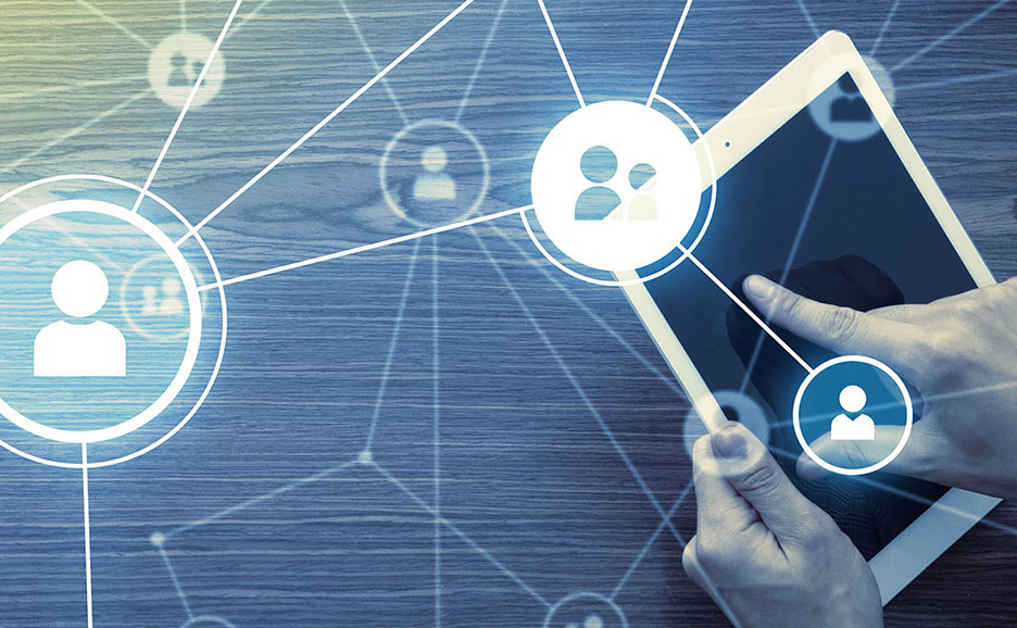 タブレットを操作する手が映る俯瞰ショット。ソーシャルネットワークやビジネスにおける人とのつながりを示す、ネットワーク図が重ねられています。