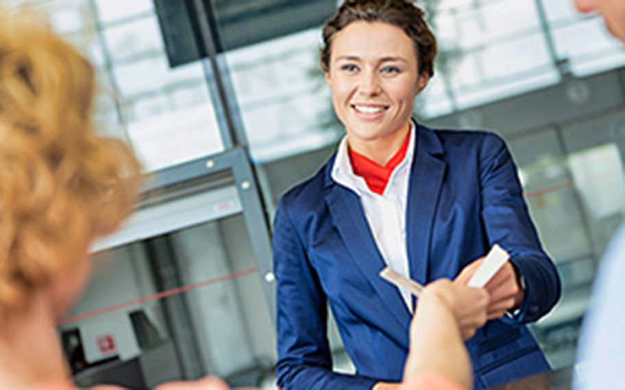 Airport staff handing boarding passes with a smile