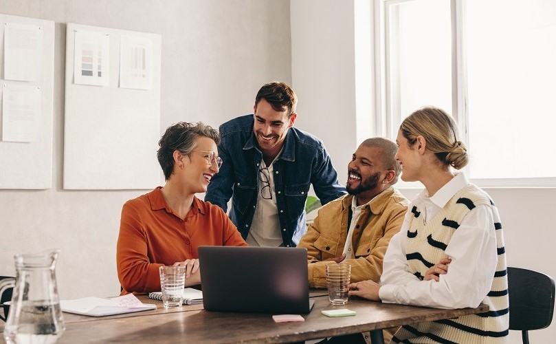 会議室で和やかにしている４人のビジネスパーソン