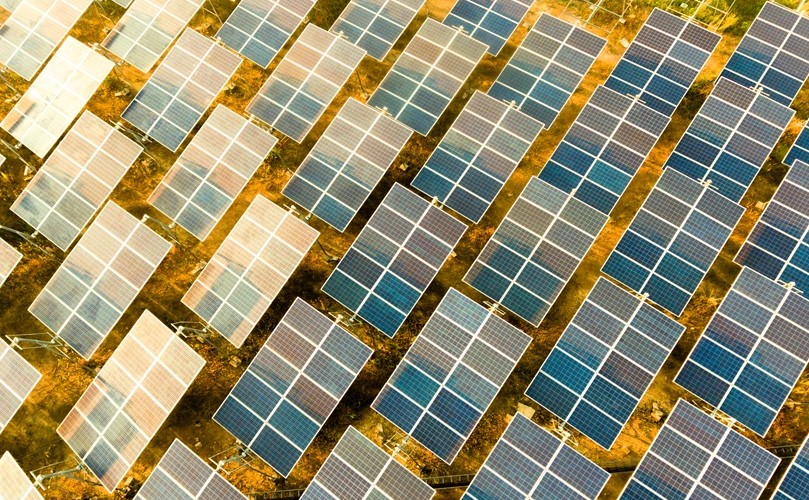 広大な土地に太陽光発電のソーラーパネルが並んでいる様子を俯瞰している
