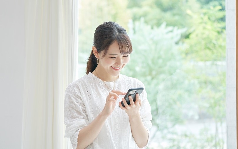 スマートフォンを操作して微笑む女性