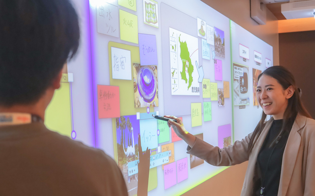 スクリーンに映し出されたオブジェクトを指しながら説明する女性