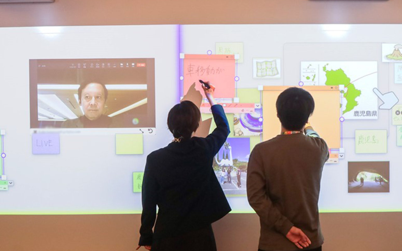 スクリーンに映し出されたデジタル付箋に手書きしている後ろ姿