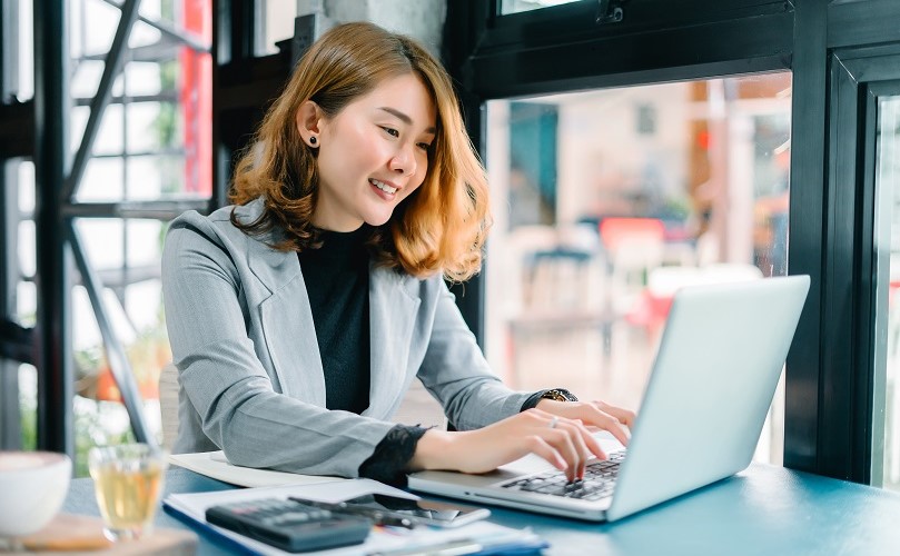 ノートPCで満足そうに仕事をする女性