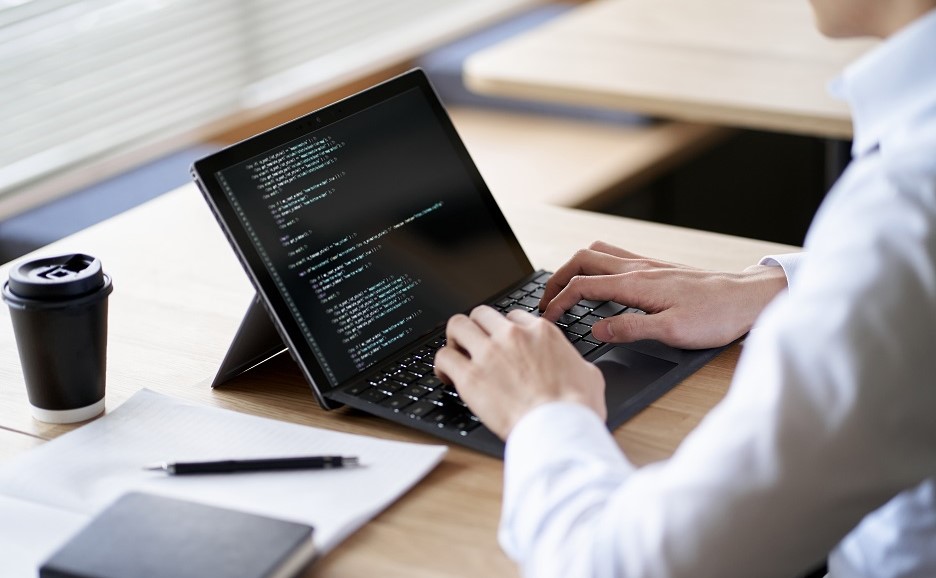 ノートパソコンでプログラミングしている人物