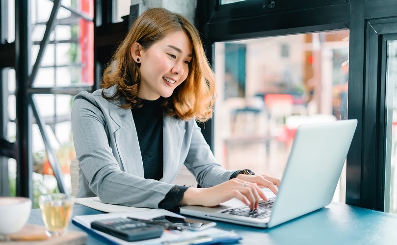 ノートPCで満足そうに仕事をする女性