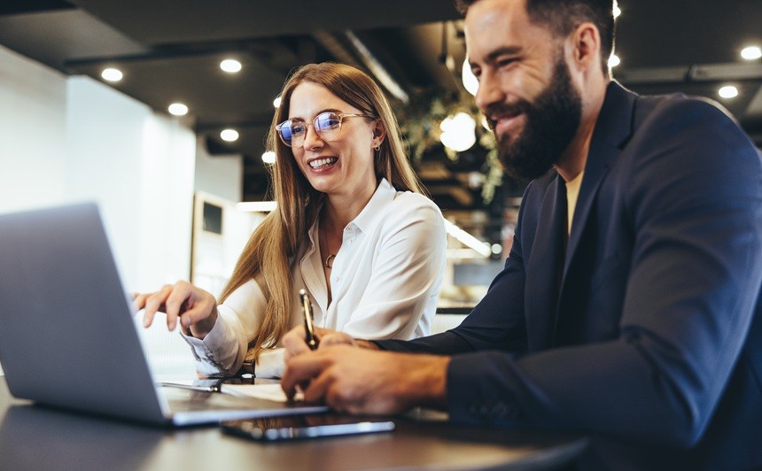 オフィスでノートパソコンを見ながら作業をしている男女のビジネスパーソン