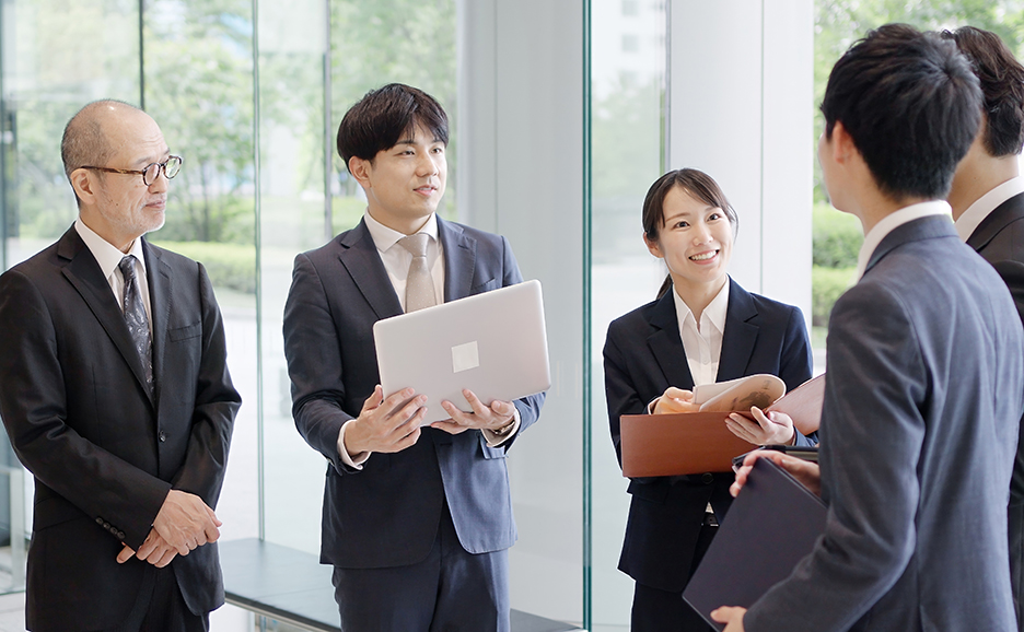 ラップトップPCや資料をもってロビーで話すビジネスマン