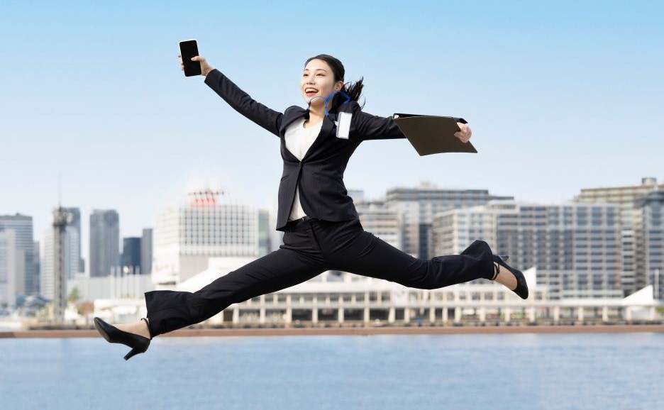 スーツを着た若いビジネスマンが笑みを浮かべて飛び跳ねる