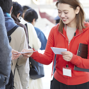 女性スタッフが来場者から紙を受け取る写真