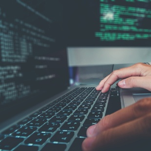 ラップトップPCでプログラムのコーディングをしている手元