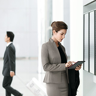 掲示板の前でタブレットを操作する女性