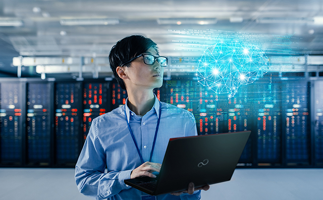 a person holding a laptop in a server room