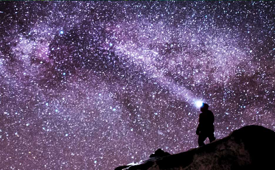 満点の紫の星空と一人の男性のシルエット