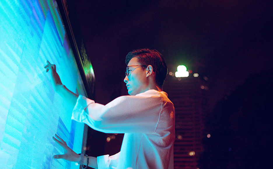 液晶モニタに手を伸ばす男性