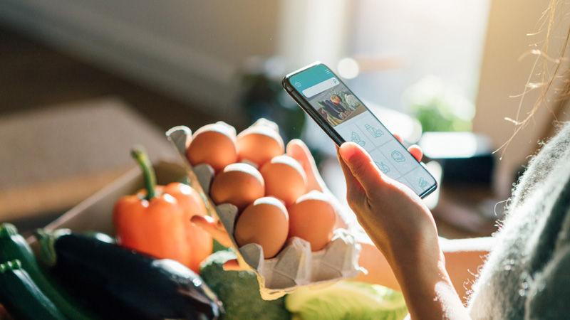 A woman is holding a smartphone over food