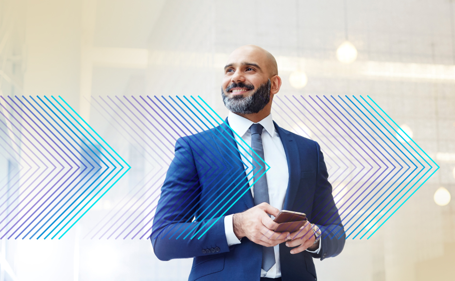 Image of a man smiling and standing with a smartphone in hand