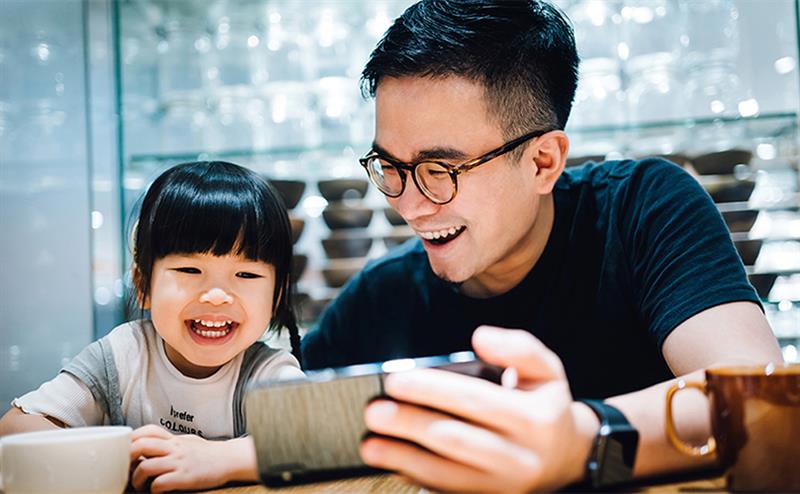 A man and a young girl looking at a tablet PC and laughing