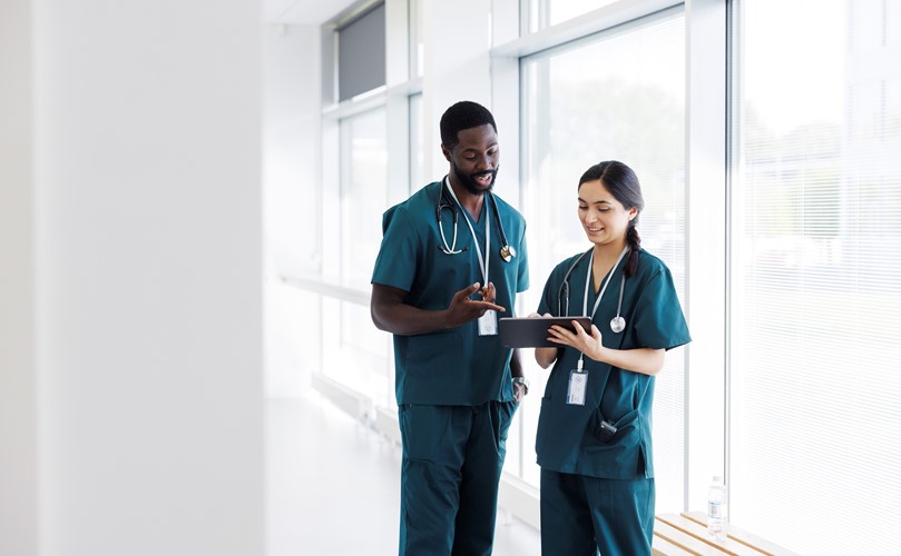 Two nurses in a corridor looking to a tablet