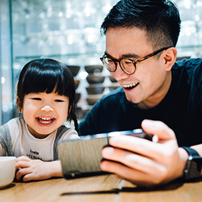 A man and a young girl looking at a tablet PC and laughing