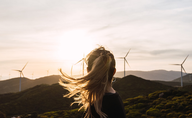 Back view of a woman looking at wind turbines