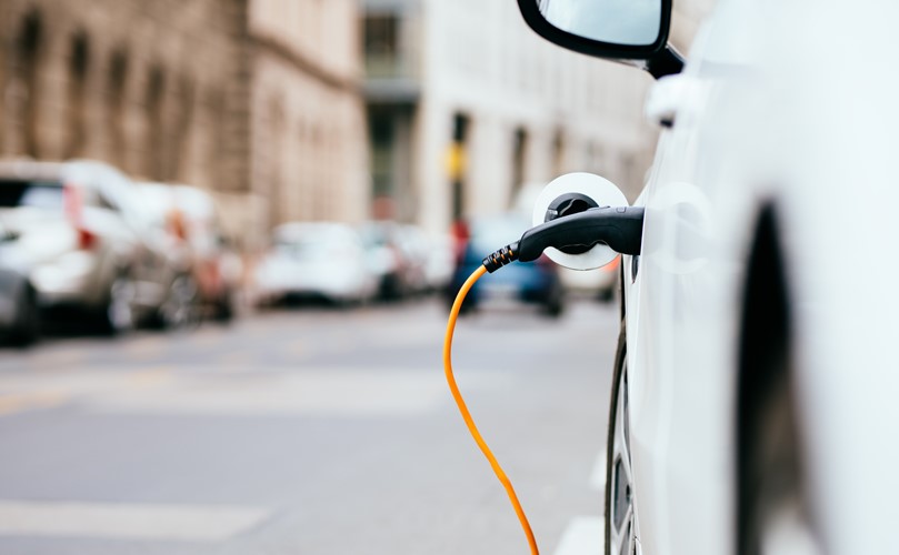 A close-up of an electric white car being charged.