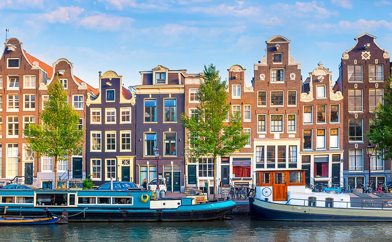 Colorful Amsterdam houses with unique facades and boats moored in the canal.