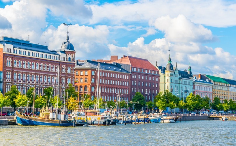 Colorful buildings line the waterfront with moored boats, under a blue sky.