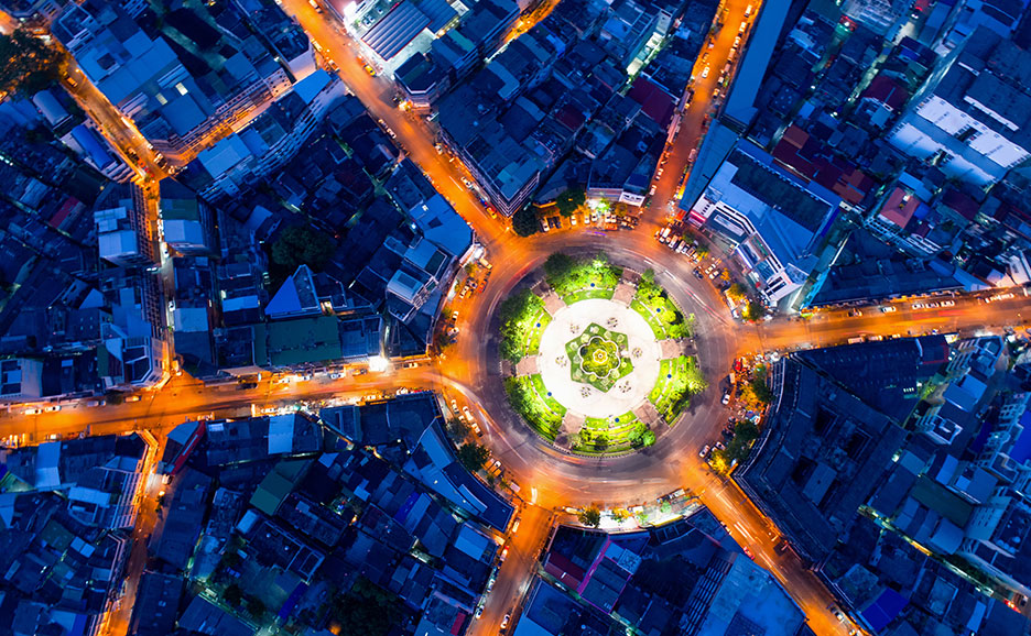 Aerial view of city roundabout at night, with glowing lights.