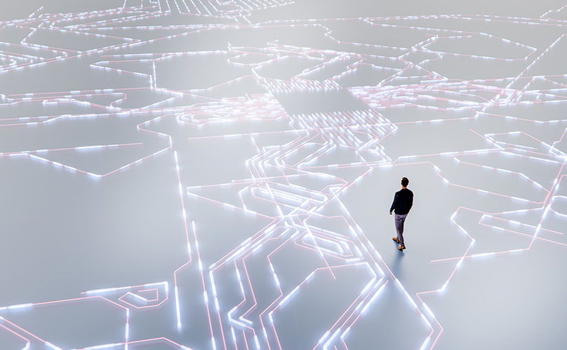 A person stands on a glowing circuit diagram. Future path, decisions.