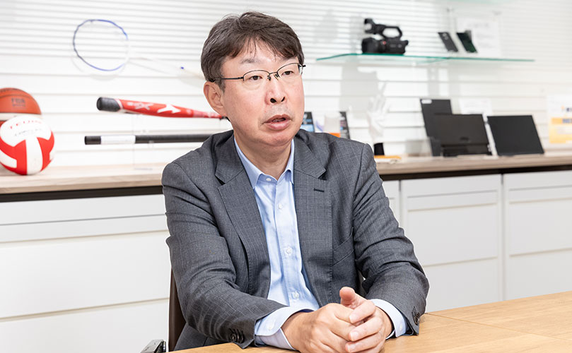 インタビューの様子を示すシーンで、帝人株式会社 グループ執行役員 デジタル・情報システム管掌の舩生 幸宏氏が写っている。